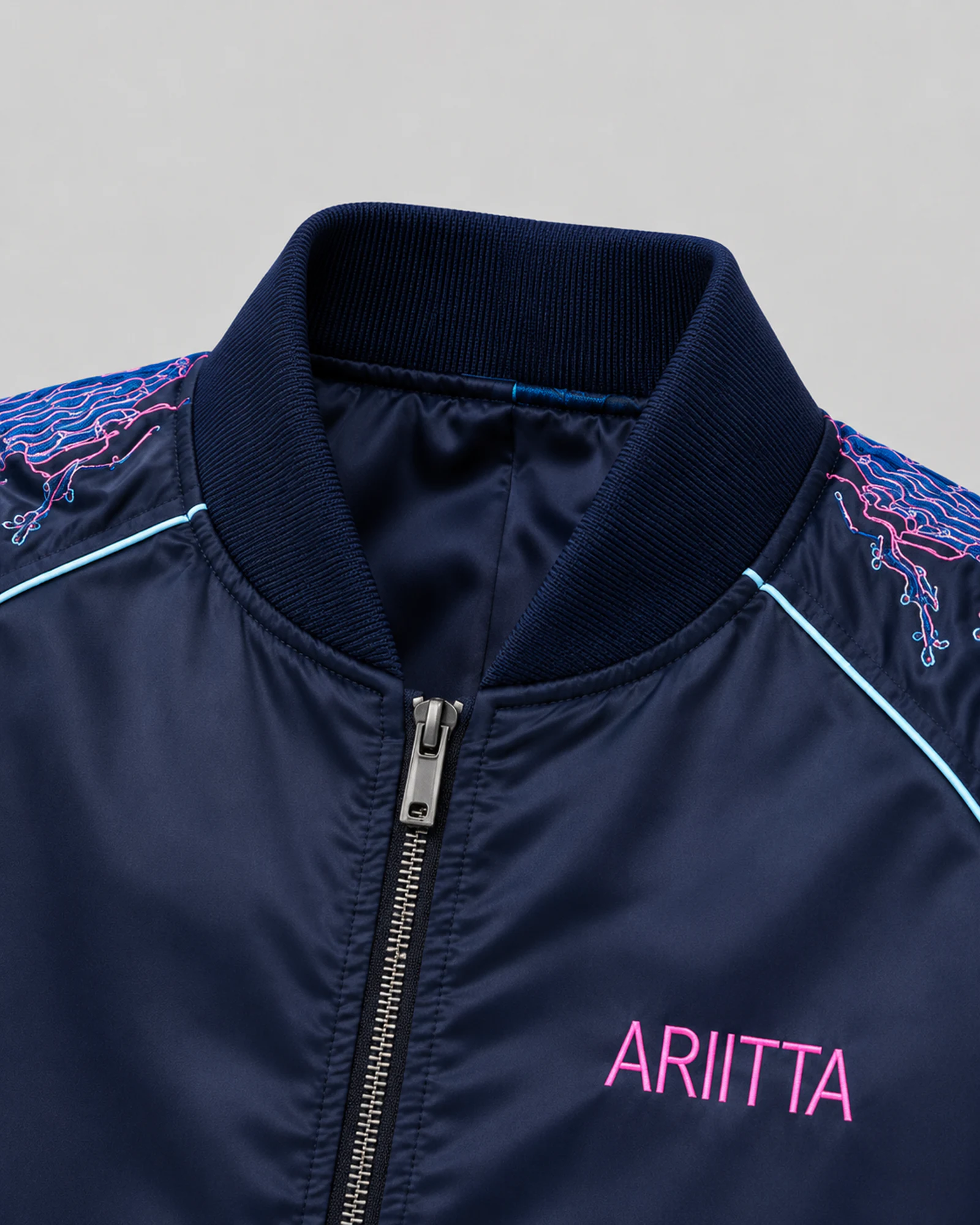 Detail of the ribbed collar, metal zip and pink ARITTA chest mark